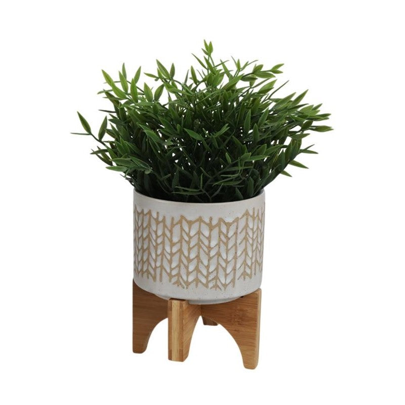 Green plant in a decorative pot on a wooden stand.