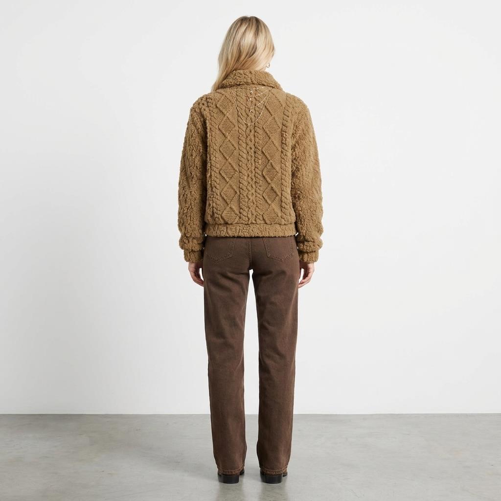 A model shows the back of a tan textured jacket and brown trousers against a plain studio backdrop.
