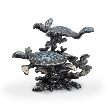 Metallic sculpture of two sea turtles swimming among coral.