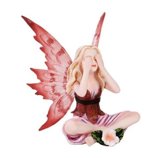Fairy figurine with pink wings sits with hands covering eyes.