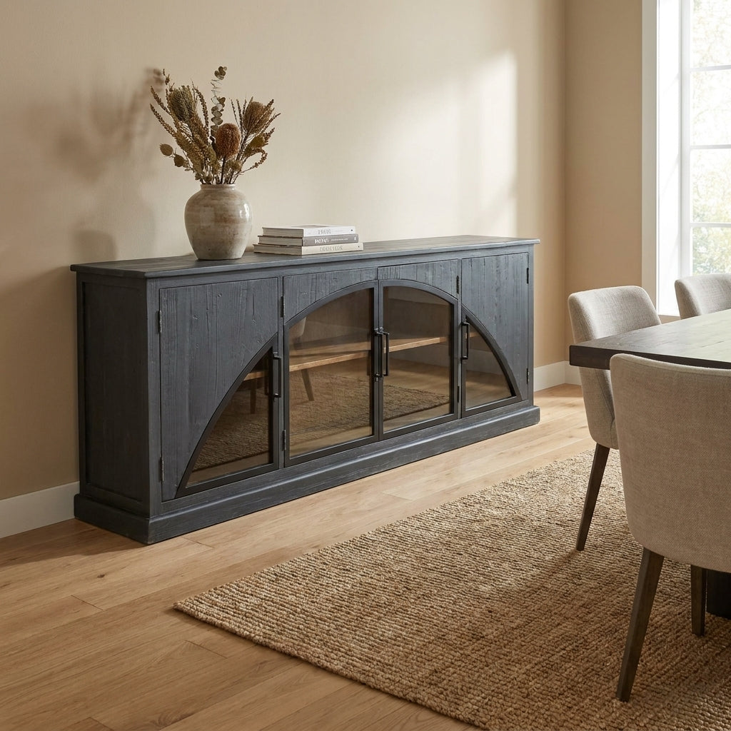 Dark wood sideboard with glass doors, vase, and books in a sunlit room.