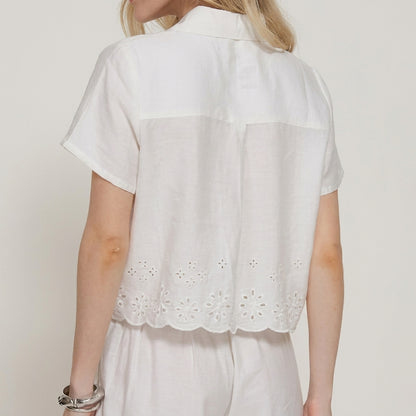 Woman in a white short-sleeve embroidered top, viewed from the back.