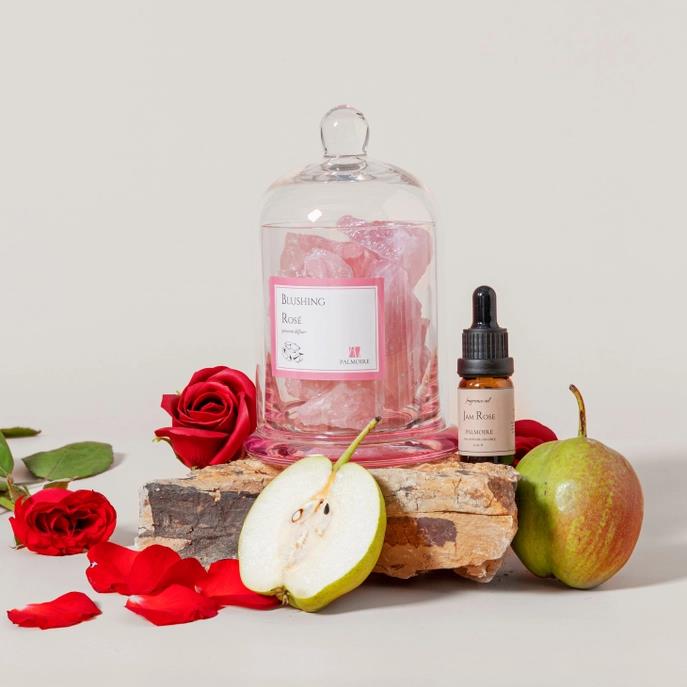 Roses, pink crystals, pears, and a dropper bottle on a wooden surface.