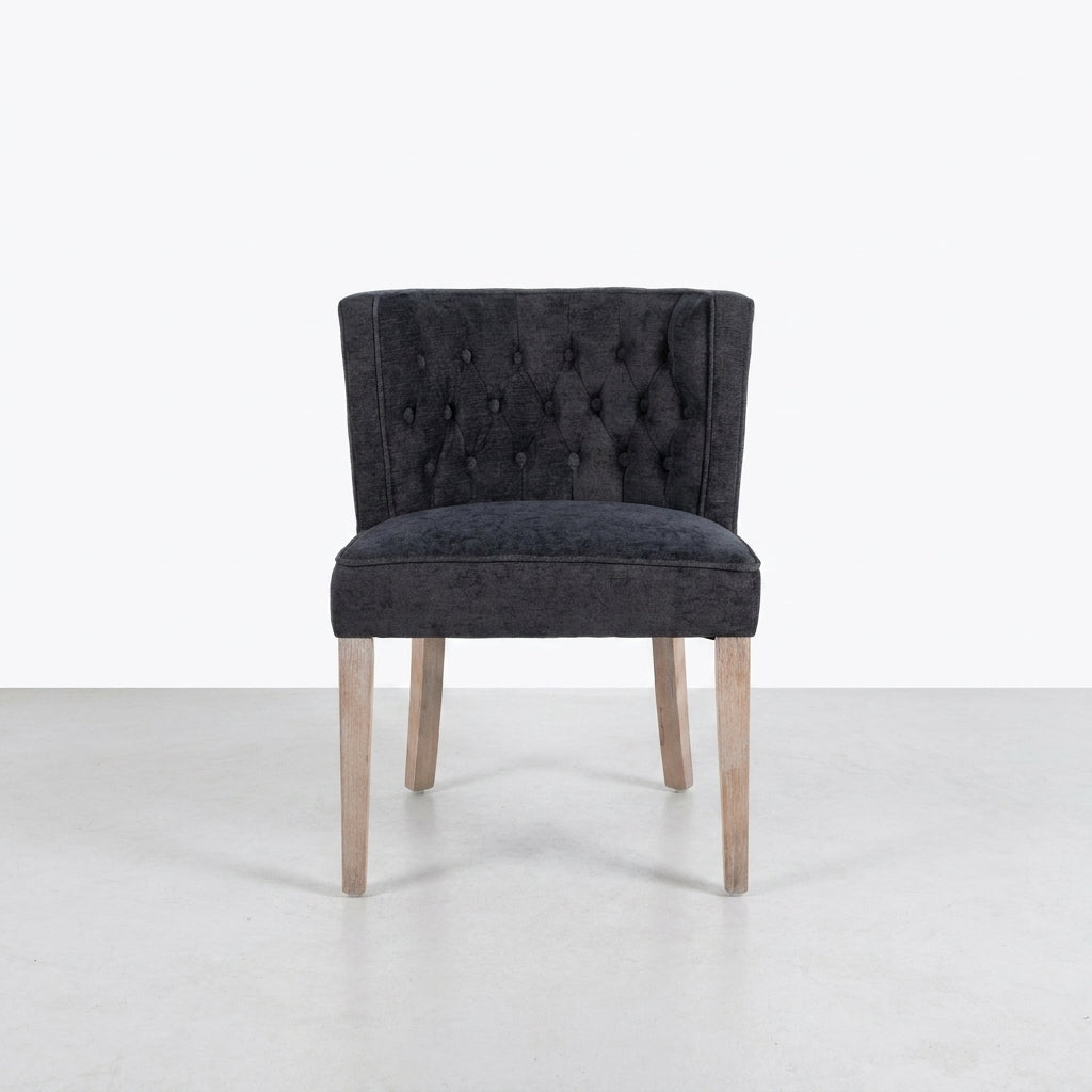 Gray tufted chair with light wooden legs on a plain background.