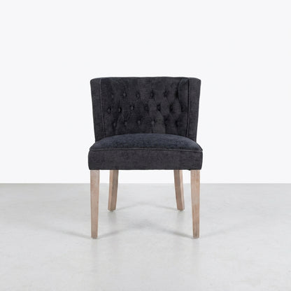 Gray tufted chair with light wooden legs on a plain background.