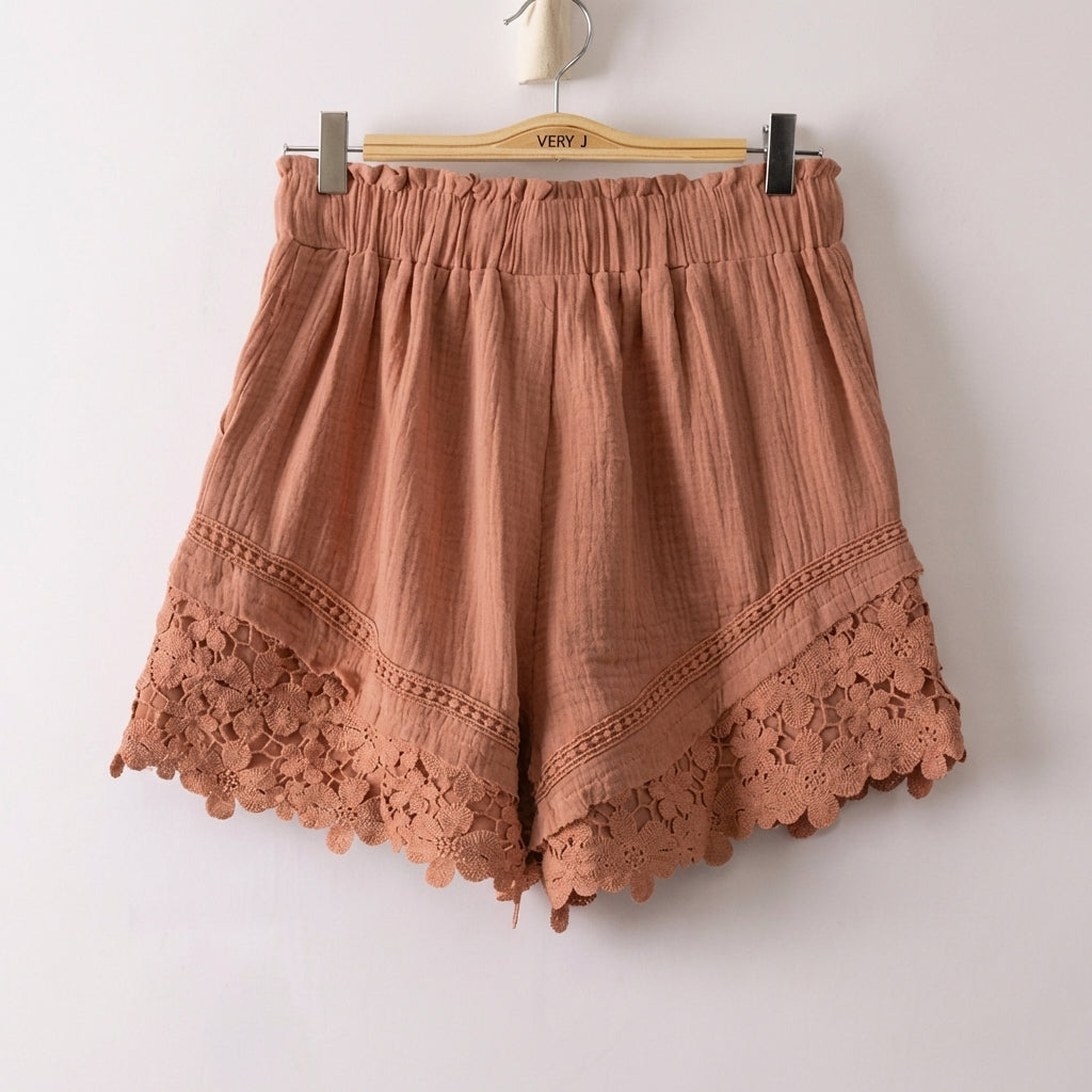 Brown shorts with lace trim on a hanger.
