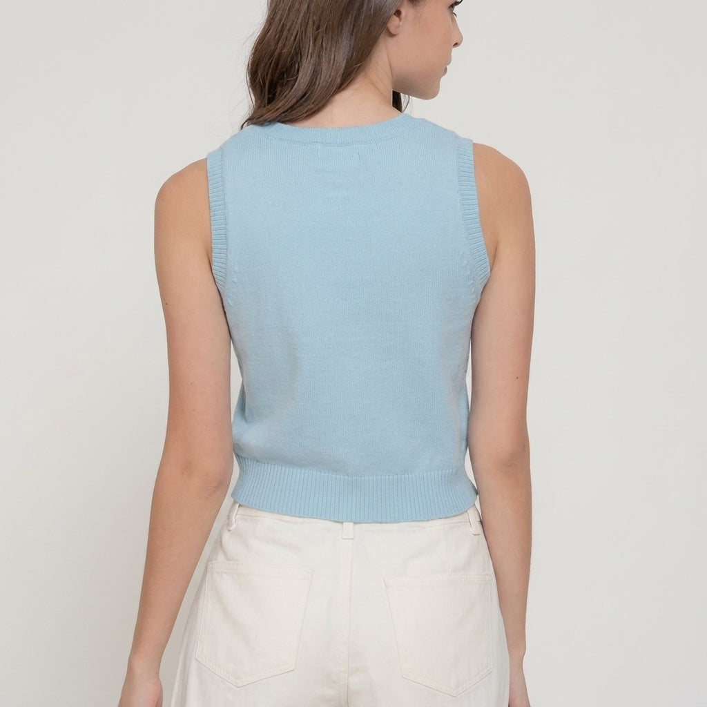 Woman in a light blue sleeveless top and white pants, facing away.