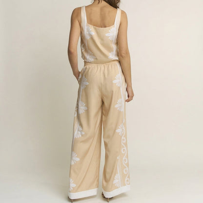 Woman in a floral beige jumpsuit, facing away.
