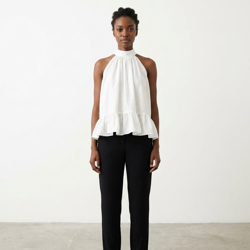 Person in white top and black pants stands against plain background.