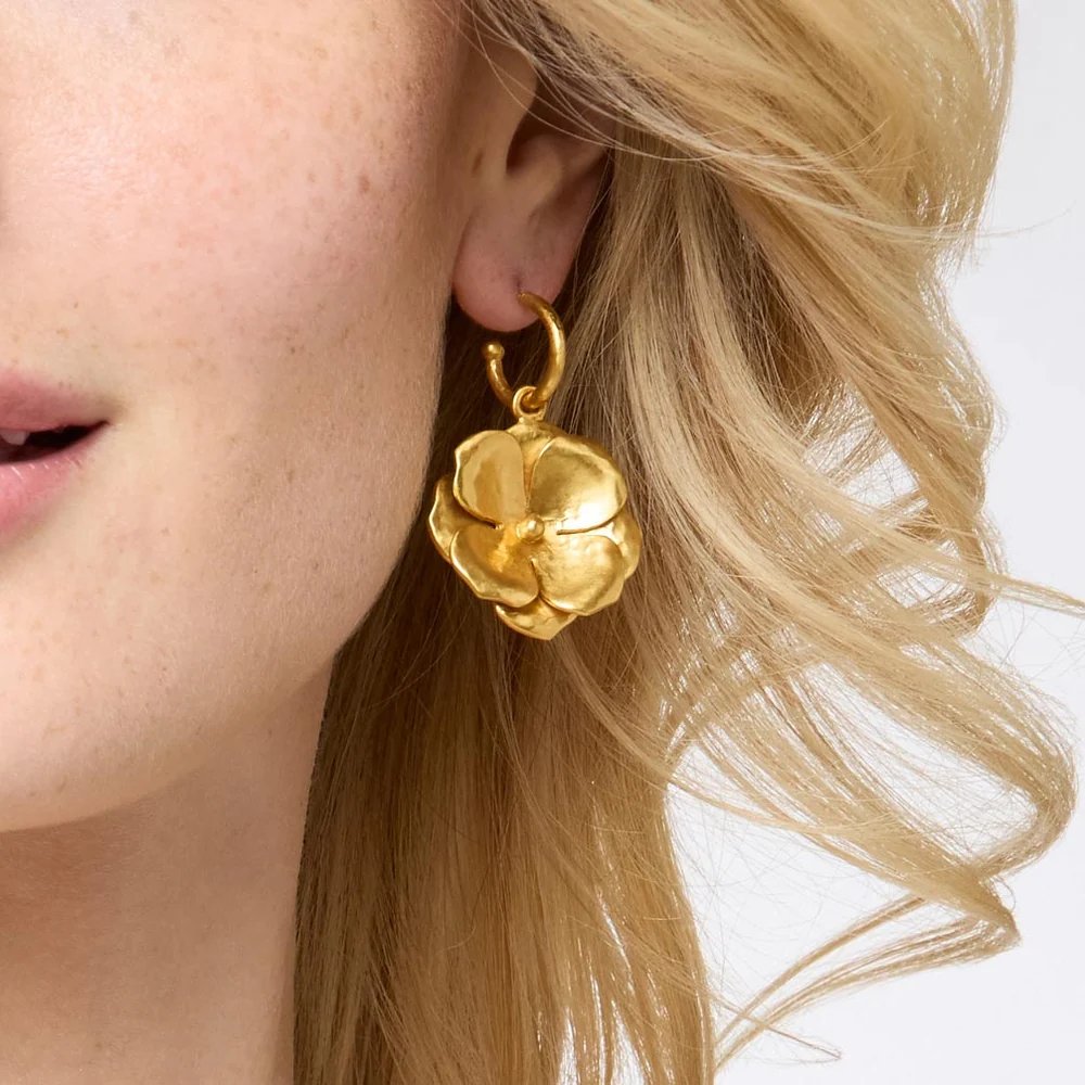 Close-up of a woman wearing a gold flower-shaped hoop earring.