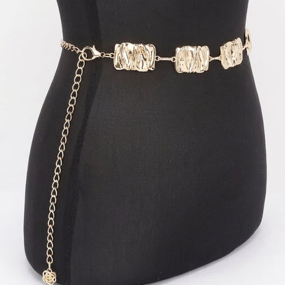 Gold chain belt on a black mannequin with textured links.