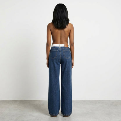 Back view of person in wide-leg jeans against a plain background.