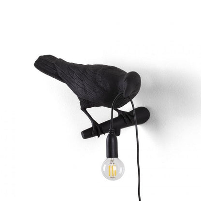 Black bird lamp with a hanging light bulb.