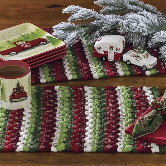 Festive setting with toy cars, plaid napkins, and a Christmas mug on a colorful mat.