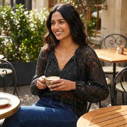 Smiling woman enjoying coffee at an outdoor café.