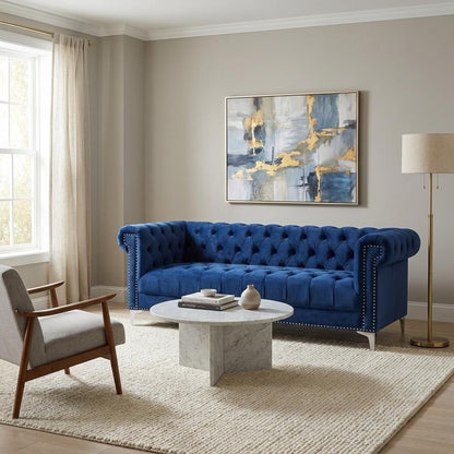 Blue velvet tufted sofa with silver legs, viewed from the back.