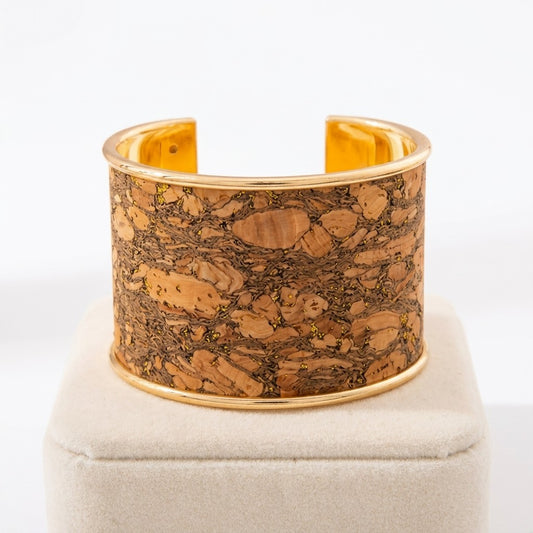Gold and cork bracelet displayed on a beige stand.