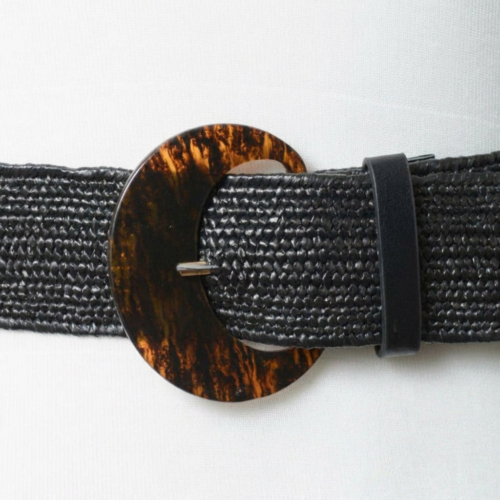 Black textured belt with a dark tortoiseshell circular buckle.