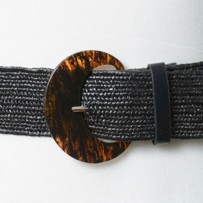 Black textured belt with a dark tortoiseshell circular buckle.