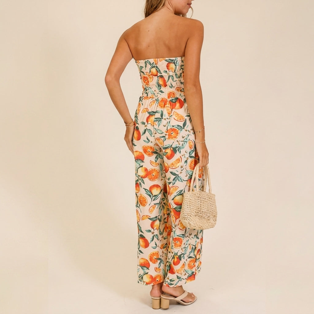Woman in citrus jumpsuit holding woven handbag, facing away.