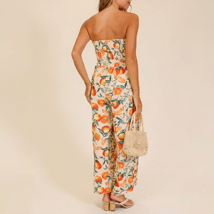 Woman in citrus jumpsuit holding woven handbag, facing away.