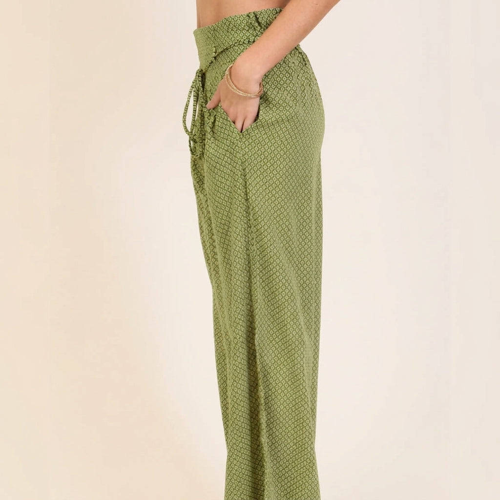 Woman in patterned green pants with hands in pockets.