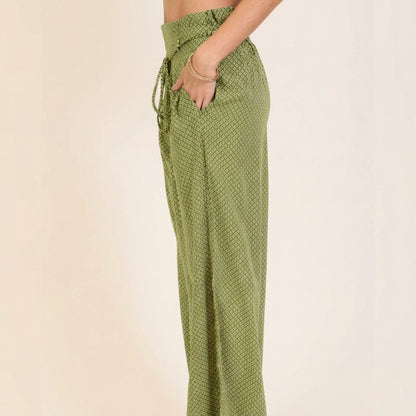 Woman in patterned green pants with hands in pockets.