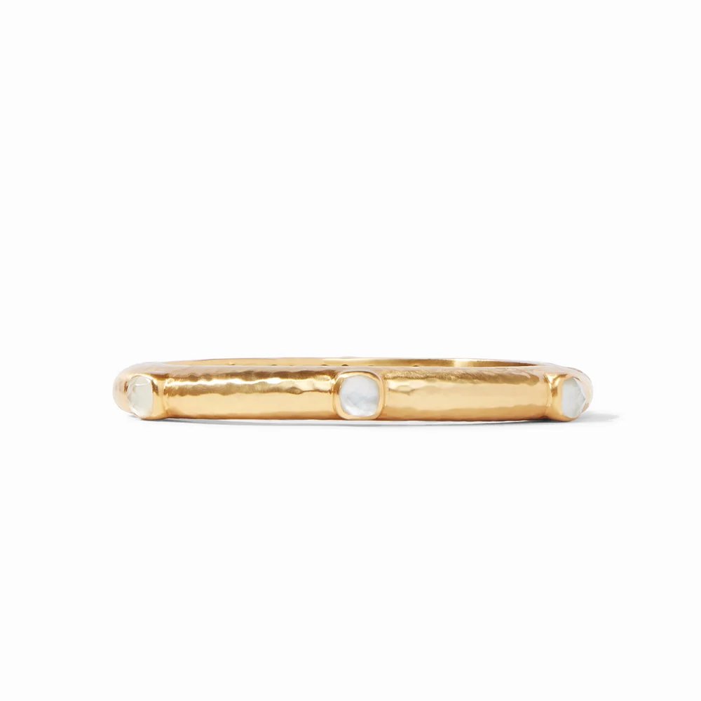 A gold ring featuring three round white stones set across its band.