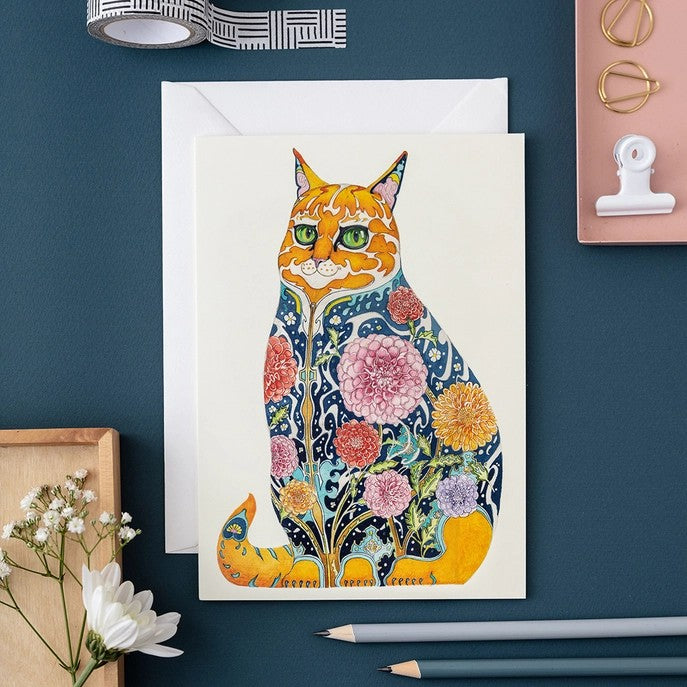 Colorful cat art with floral patterns beside stationery items.