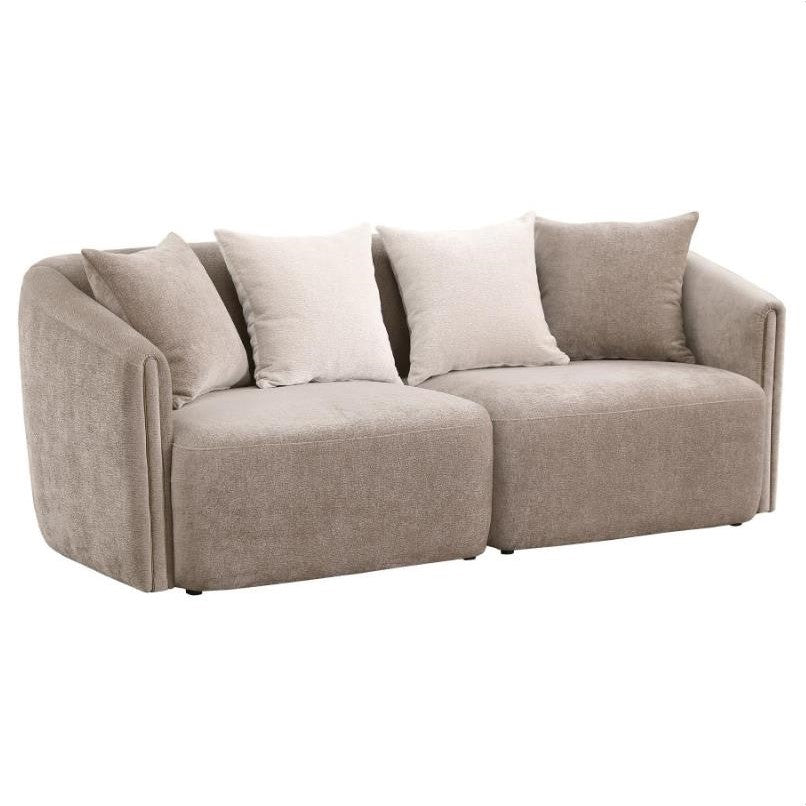 Beige sofa from the back with curved edges and multiple cushions.