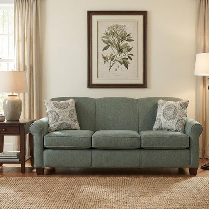 Cozy living room with green sofa, floral pillows, and botanical wall art.