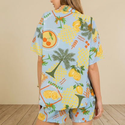 Person in vibrant fruit-patterned shirt with palm trees and lemons on a light blue background.