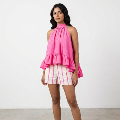 Woman in pink ruffled sleeveless top and striped shorts.