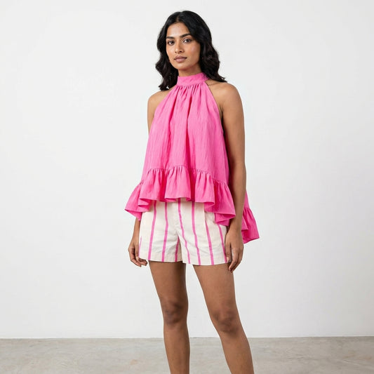 Woman in pink ruffled sleeveless top and striped shorts.