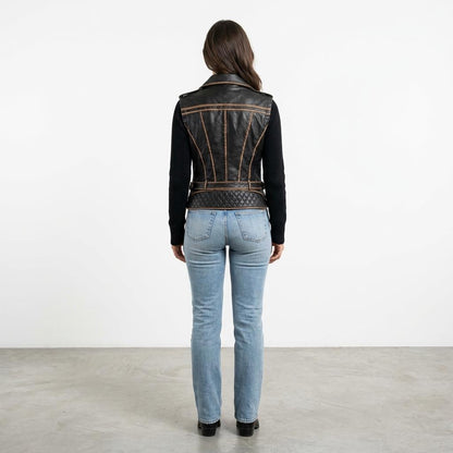 A woman models a black leather vest and light blue jeans, viewed from behind.