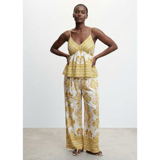 Model in yellow-patterned summer attire with spaghetti straps and wide-leg pants.