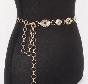 Gold chain belt with ornate accents on a black mannequin.