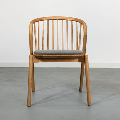 Wooden chair with a grey cushion on a plain background.