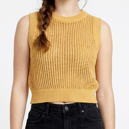 Woman in yellow crochet top and black jeans.