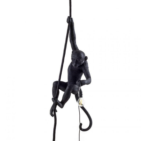 Black monkey lamp holding a light bulb while climbing a rope.