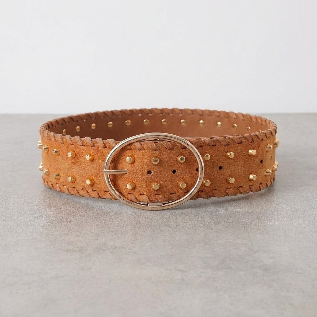 Brown studded leather belt with oval buckle on a gray surface.