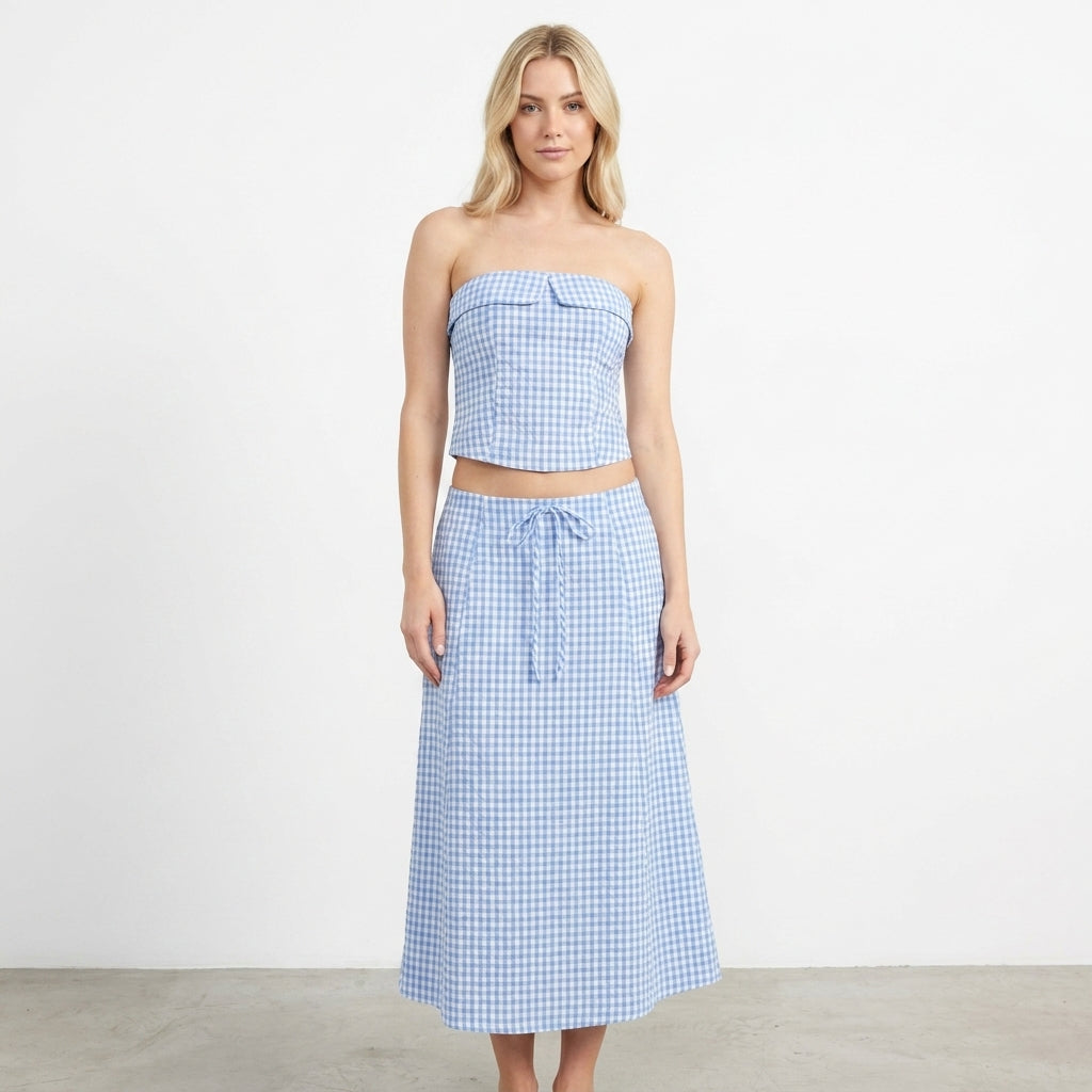 Woman in blue gingham strapless top and skirt on white background.