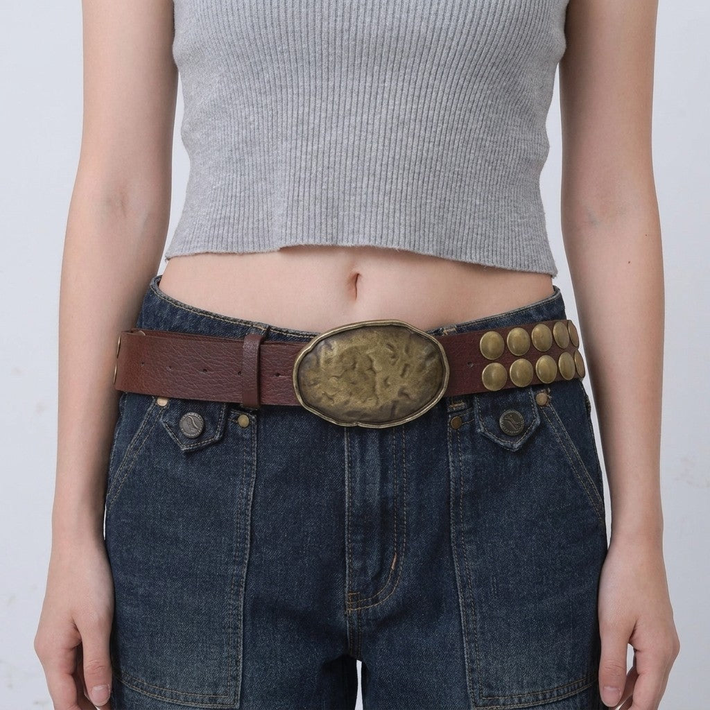 Gray crop top, denim jeans, and a large brown belt with detailed buckle.