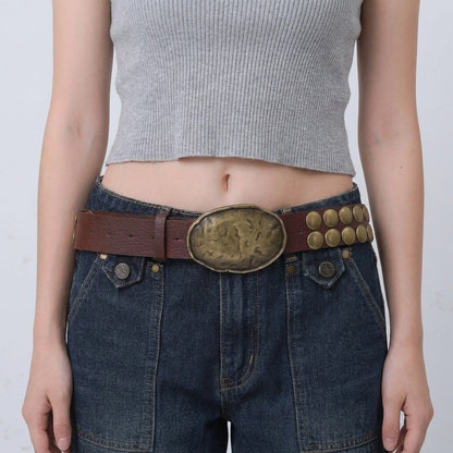 Gray crop top, denim jeans, and a large brown belt with detailed buckle.