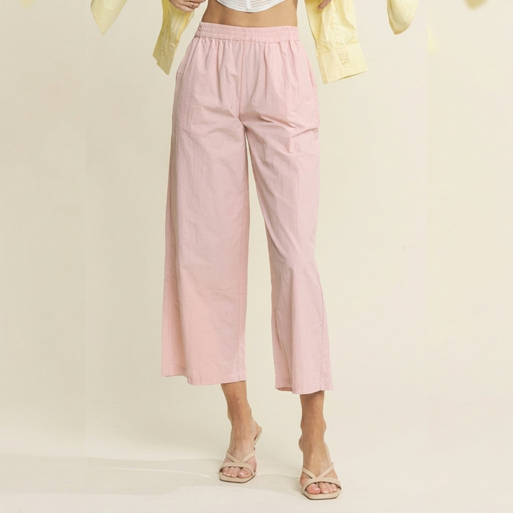 Woman in pink pants, yellow shirt, and sandals, posing indoors.