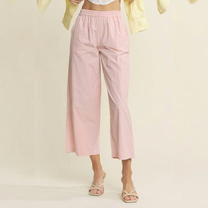 Woman in pink pants, yellow shirt, and sandals, posing indoors.