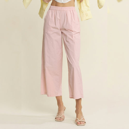 Woman in pink pants, yellow shirt, and sandals, posing indoors.
