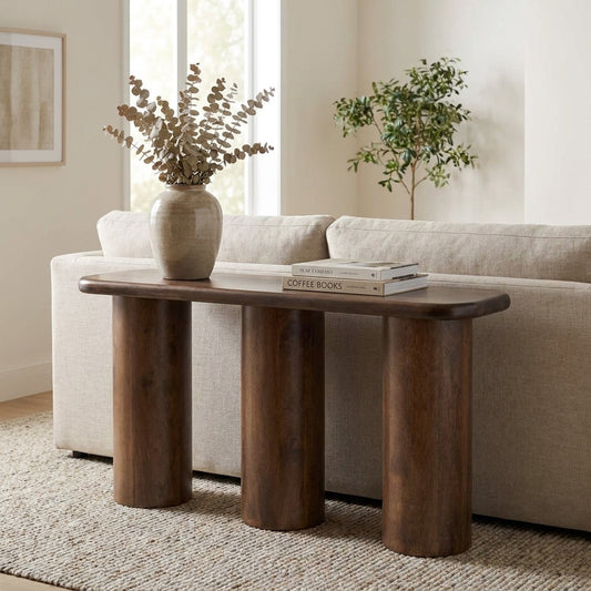 Wooden console table behind sofa with vase and books.