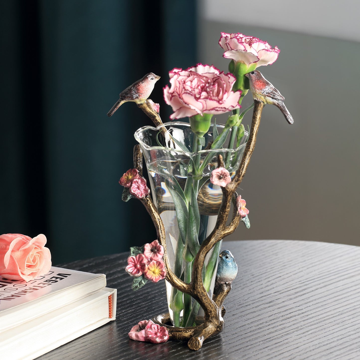 Glass vase with pink flowers, perched birds, and ornate branch holder.
