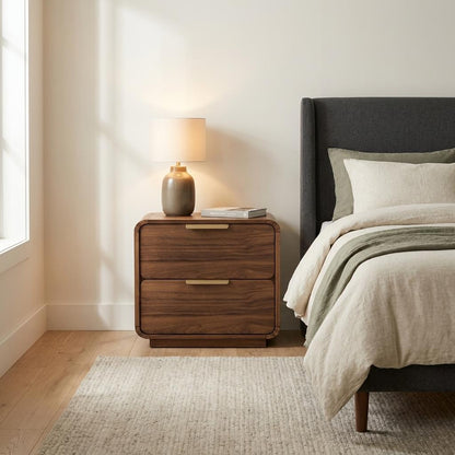 Cozy bedroom with wooden nightstand, lamp, and soft bedding.